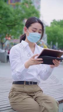青年女人戴着<strong>口罩</strong>使用平板电脑